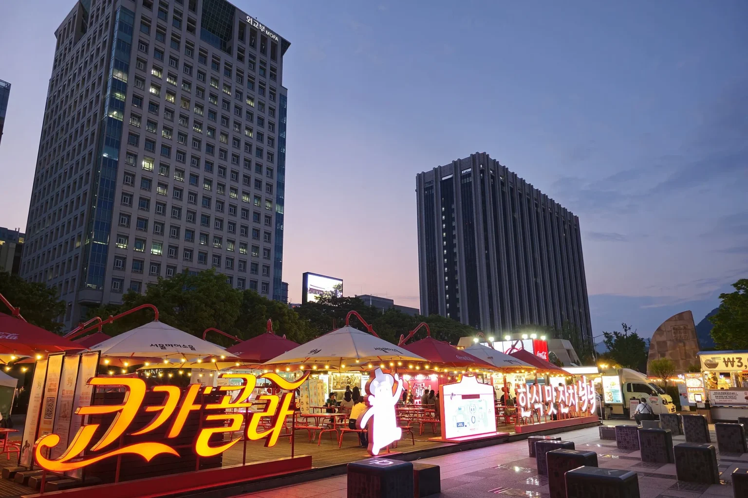 Food festival stalls and crowds lit up in the evening